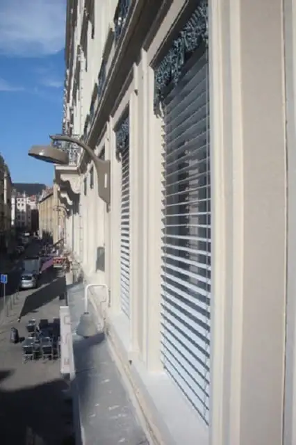 Brise-soleil orientables le long de la façade, au-dessus de la rue