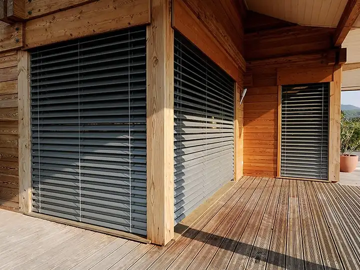 Brise-soleil orientables à lames aluminium sur une façade en bois