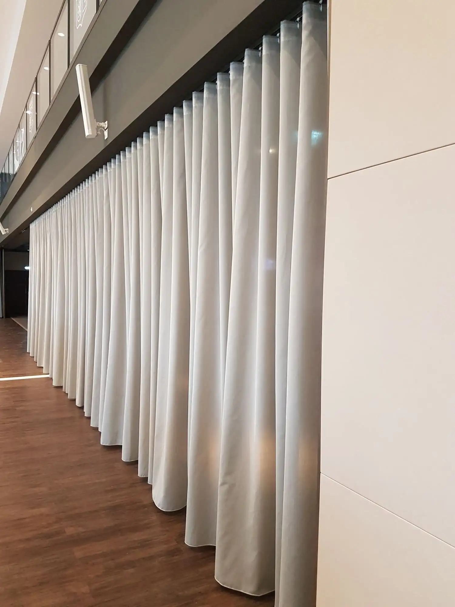 Le grand rideau blanc du salon du Groupama Stadium, déployé en plis réguliers du plafond au parquet