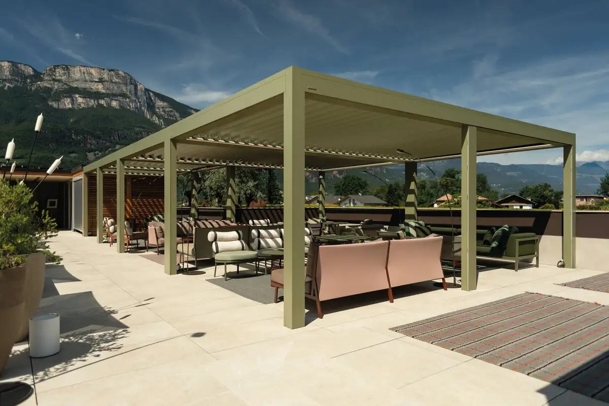 Grande pergola à lames vert olive couvrant une terrasse en hauteur, face aux montagnes