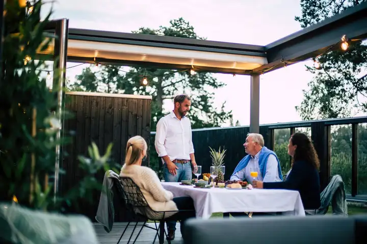 Dîner entre amis le soir sous une pergola à toile éclairée par des guirlandes