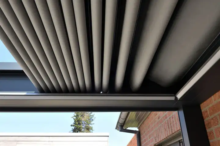 Toile grise plissée d’une pergola à toile repliable, vue de dessous contre le ciel
