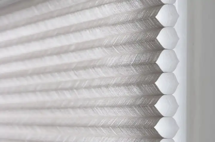 Gros plan sur un store plissé alvéolaire blanc : les alvéoles du tissu vues de profil