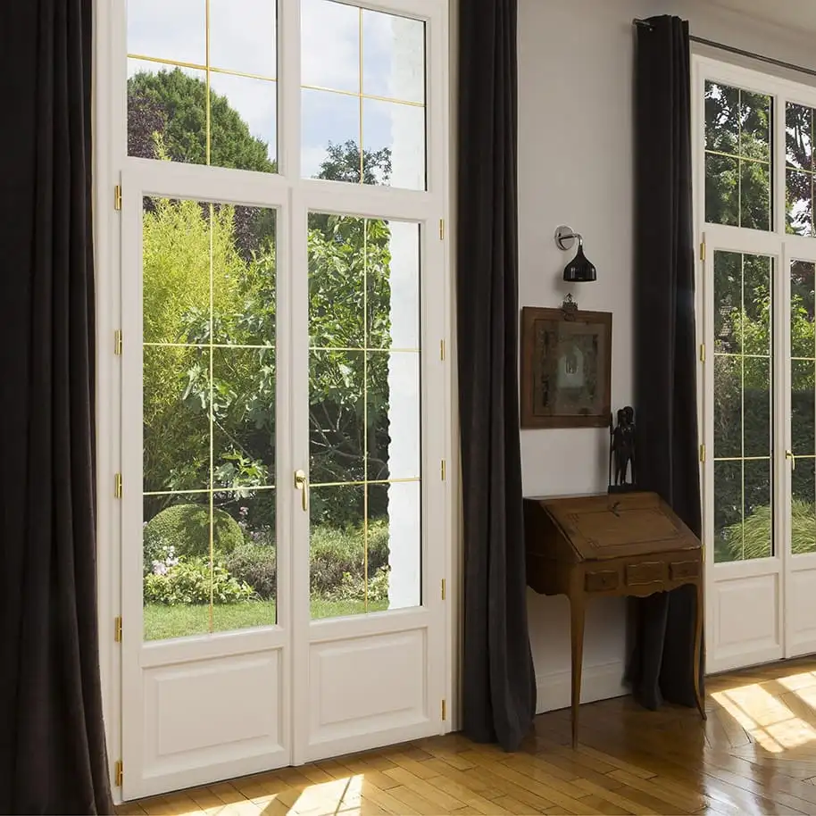 Porte-fenêtre blanche à petits bois ouverte sur un jardin, vue depuis la pièce