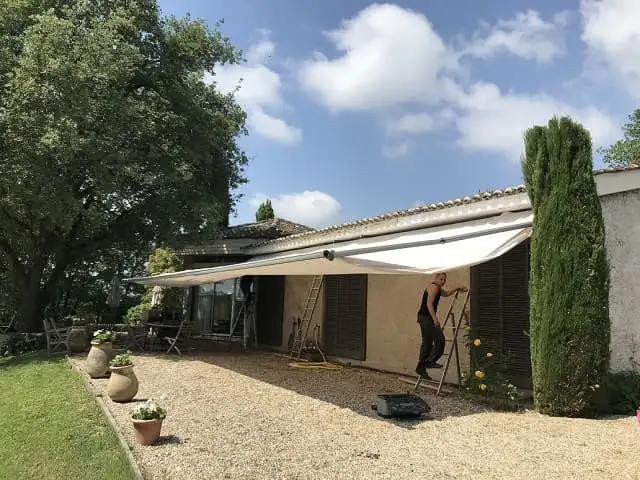 Fin de pose : un technicien sur son escabeau, au bout du store déployé