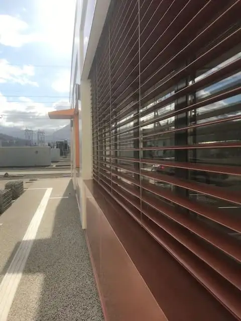 Lames orientables couleur cuivre, vues en enfilade le long de la façade