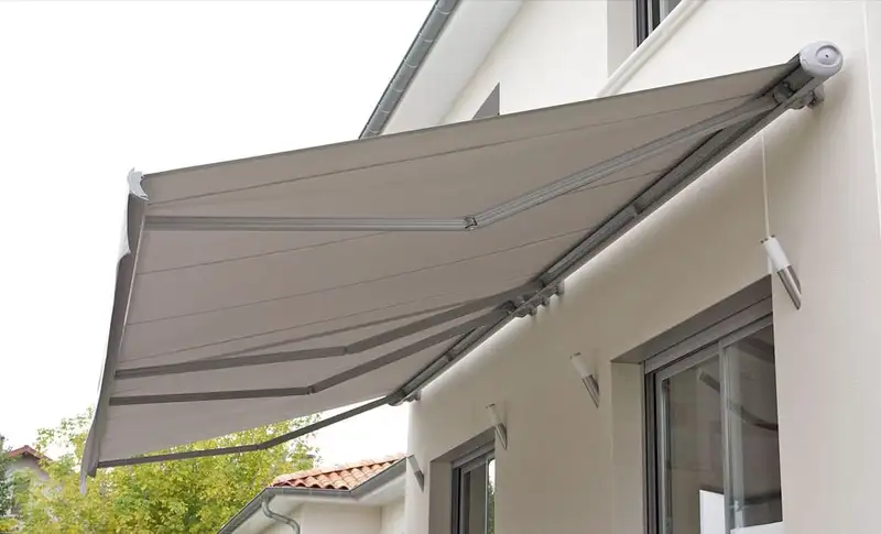 Store banne gris à coffre intégral déployé contre la façade blanche d’une maison