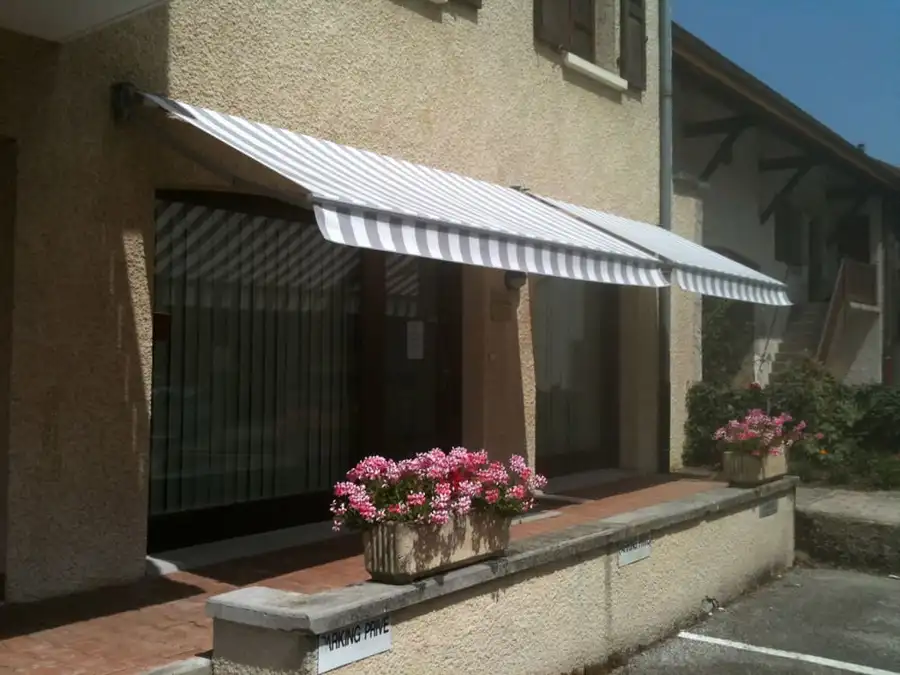 Stores bannes rayés gris et blanc au-dessus des vitrines d’une agence MMA, à Ferney-Voltaire