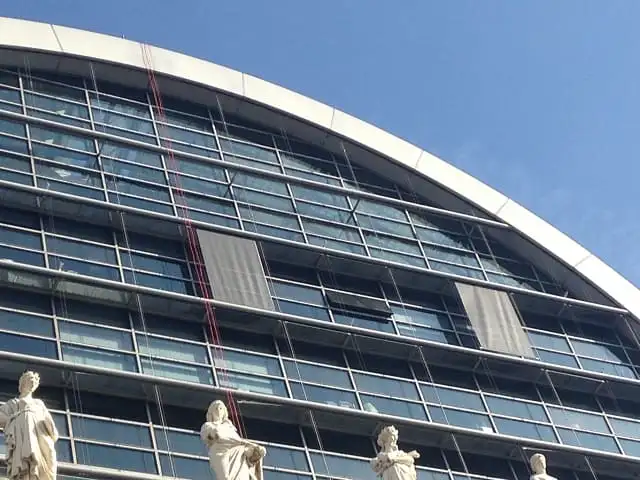 Cordes des cordistes le long de la façade vitrée de l’Opéra de Lyon, entre deux stores baissés