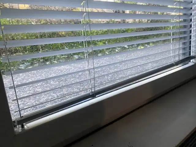 Gros plan sur les lames en aluminium d’un store vénitien et son câble de guidage latéral