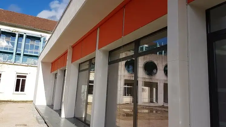 Alignement de stores orange sous l’avancée du toit