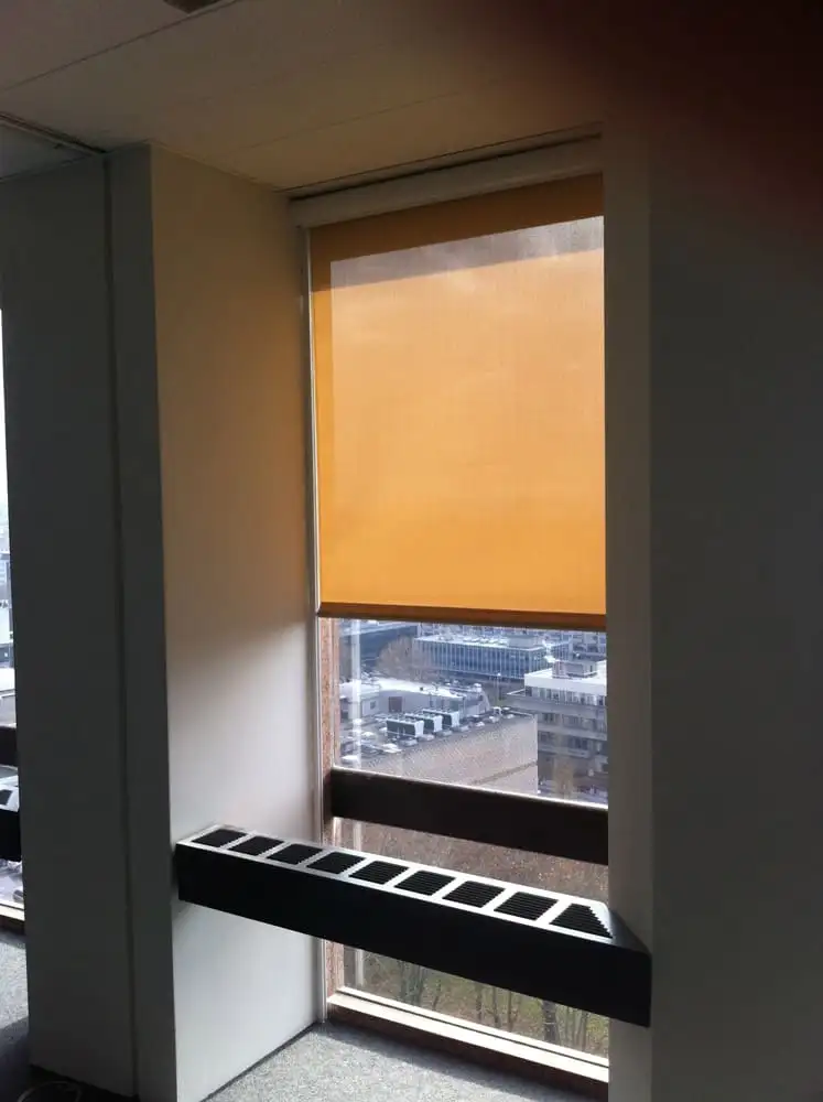 Store enrouleur à toile jaune baissé à mi-hauteur devant une fenêtre de la tour, vue sur Lyon