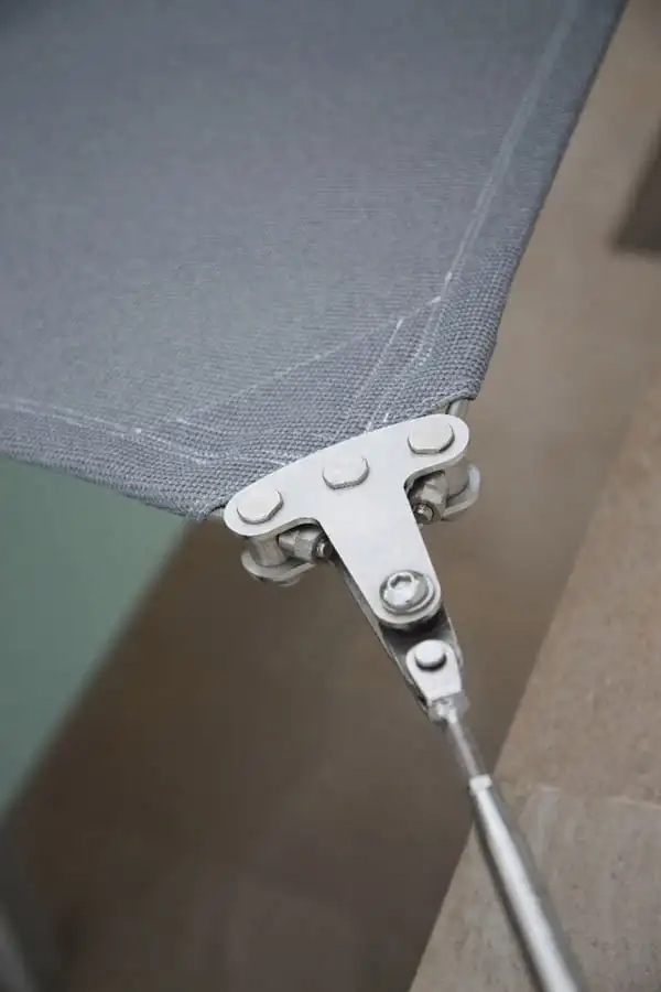 Angle d’une voile d’ombrage grise tenu par une platine de fixation en inox